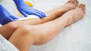 A person applying wax to a leg