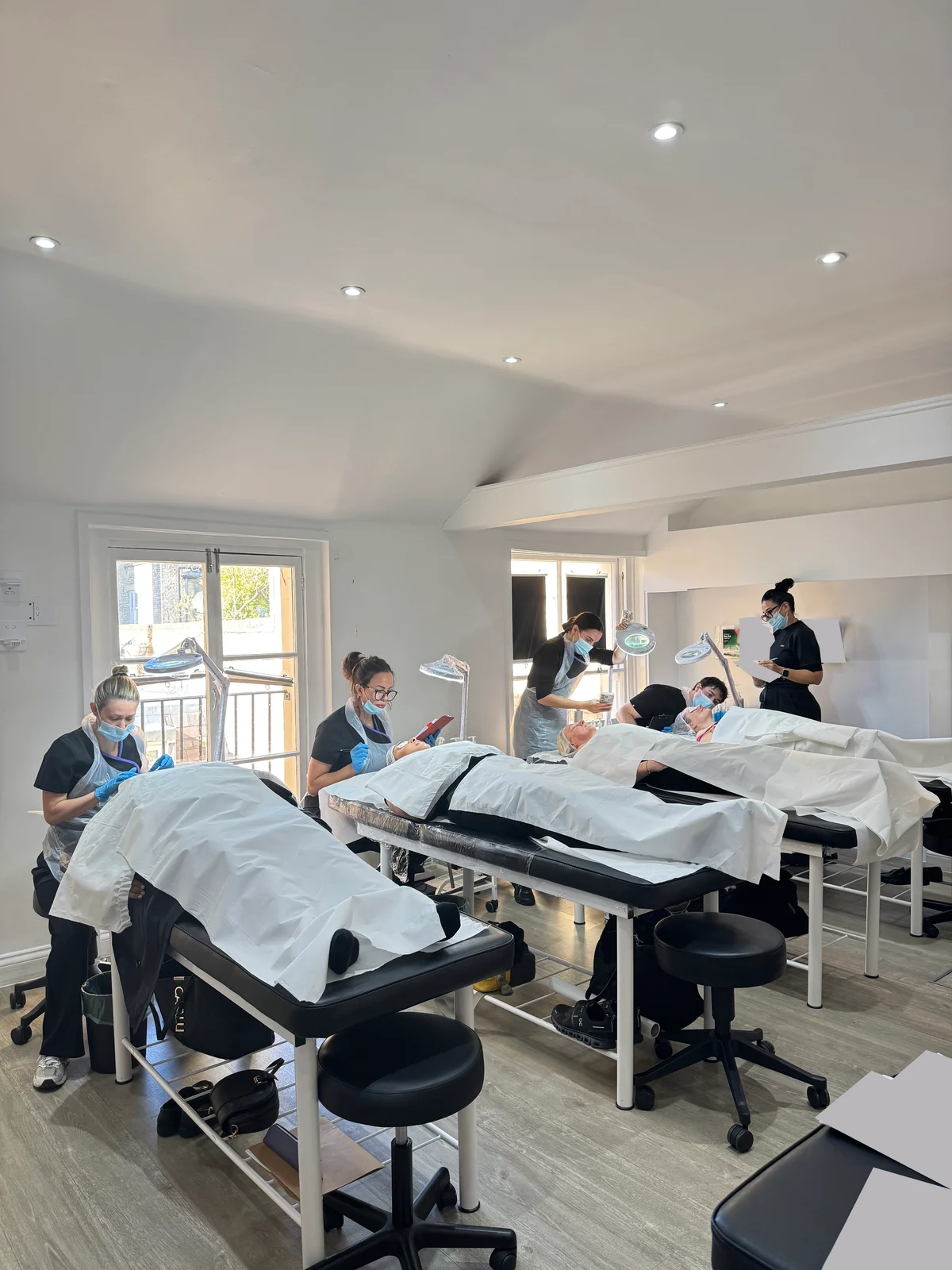 Group of students working with models at treatment beds while their tutor observes.